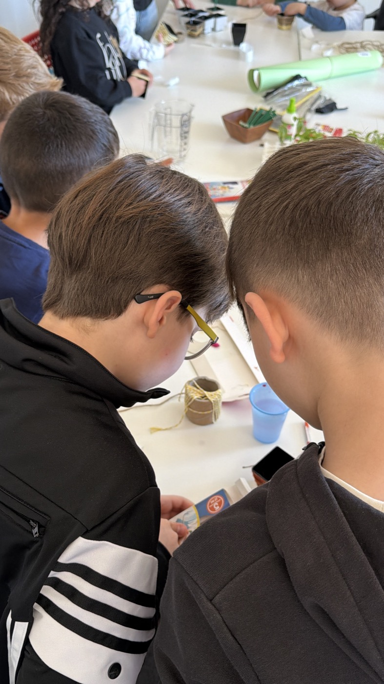 Bambini lavorano ai vasetti intorno a un tavolo