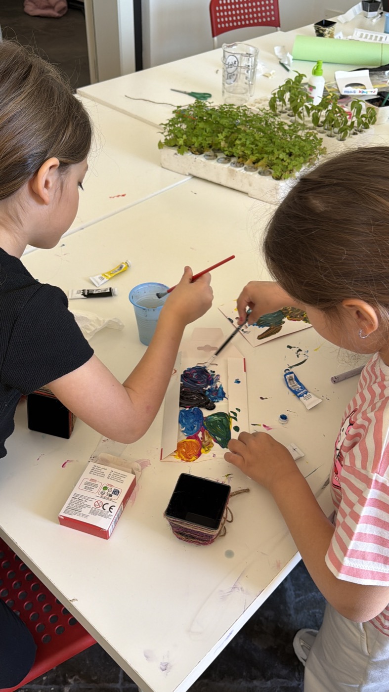 Due bambine dipingono i vasetti al tavolo