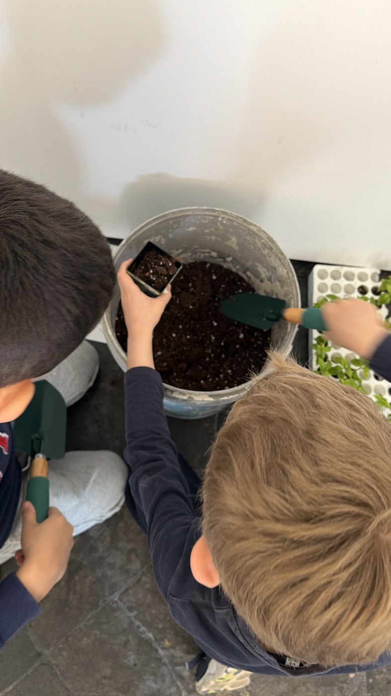Bambini riempiono i vasetti con il terriccio